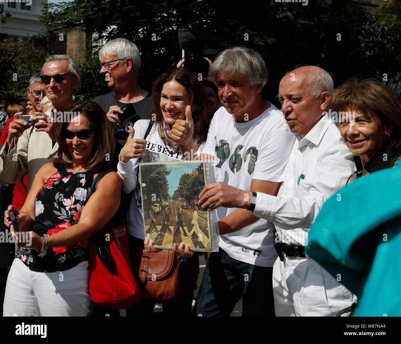 London, Britain. 8th Aug, 2019. Beatles fans pose for photos with an original copy of the album cover of 'Abbey Road' in London, Britain, Aug. 8, 2019. Exactly 50 years ago, Beatles members John Lennon, Paul McCartney, George Harrison and Ringo Starr walked on the zebra crossing outside their recording studio in north London to get the cover shot for the album 'Abbey Road'. Credit: Han Yan/Xinhua/Alamy Live News Stock Photo