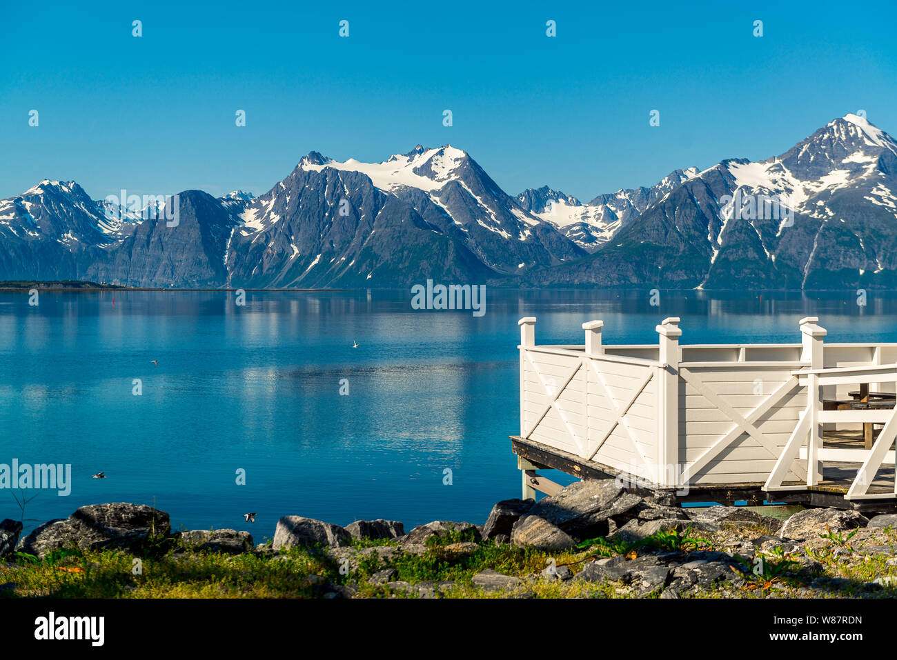 Picnic site rest stop area wooden table decoration and norwegian flag on lake fjord shore. Holidays relaxation on trip. Scandinavia Europe. Stock Photo