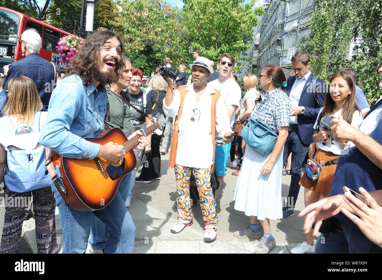 Abbey Road, NW8, London, UK, 8th August, 2019. A Beatles busker entertains the fans as they celebrate the 50th anniversary of The Beatles album Abbey Road. Credit: David Bronstein/Alamy Live News Stock Photo