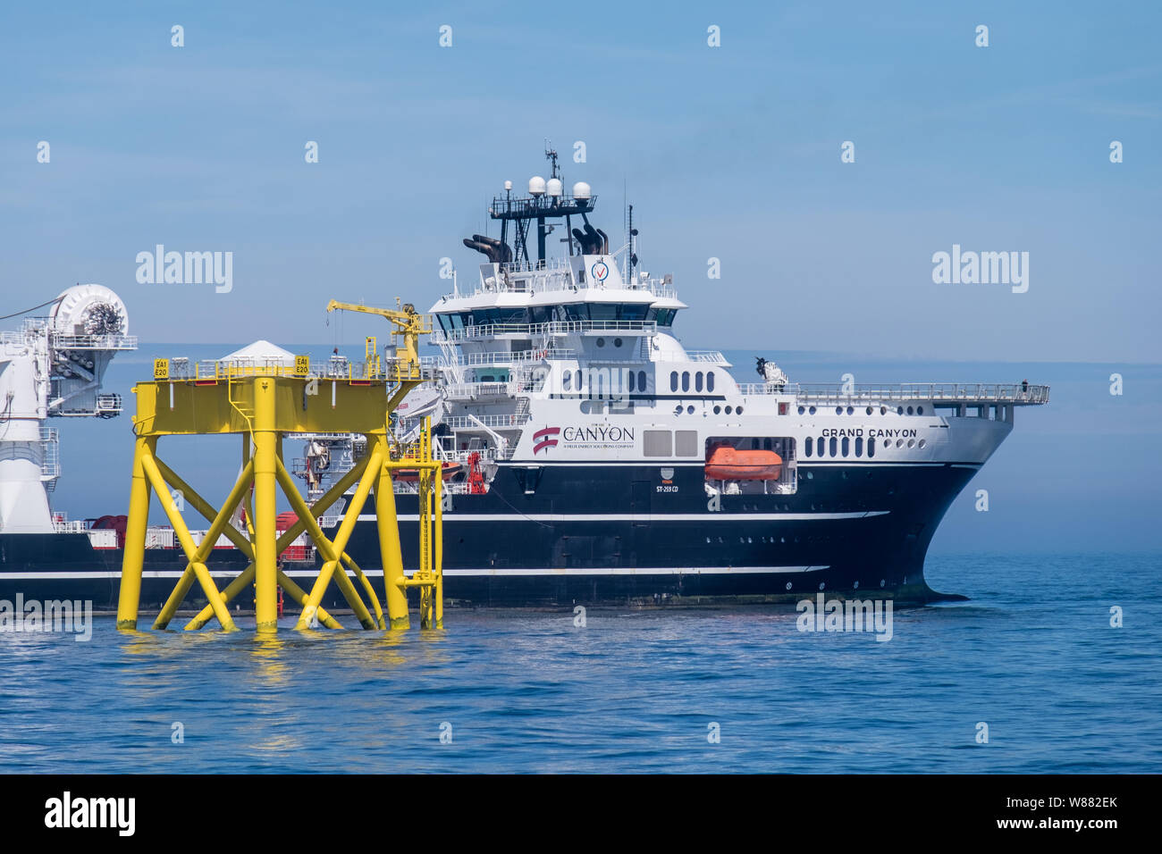 East Anglia ONE Offshore Wind Farm during construction with the construction support vessel, Grand Canyon, working on subsea cables close to one of the wind turbine jacket installations Stock Photo
