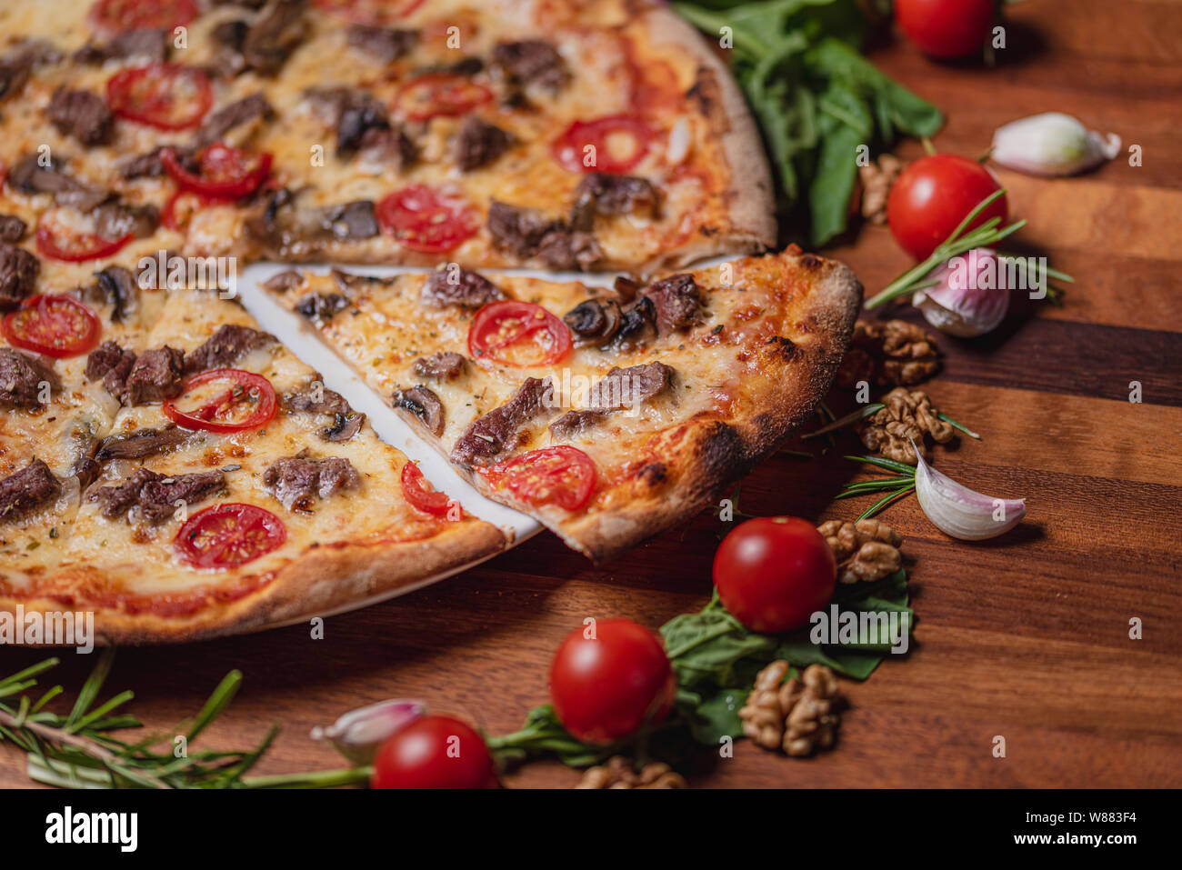 pizza with meat mushrooms and tomato on wooden table background top view Stock Photo