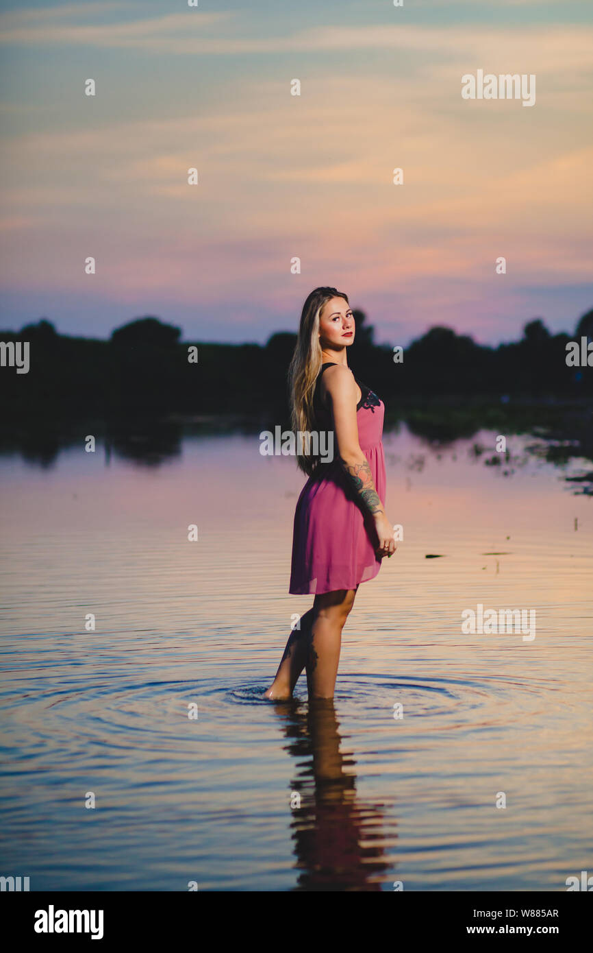 Beautiful blond model with long hair standing in the water Stock Photo ...