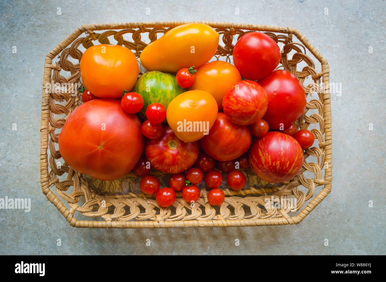 Different types of organic tomatoes in a basket - orange, green, red tomatoes, cherry tomatoes Stock Photo