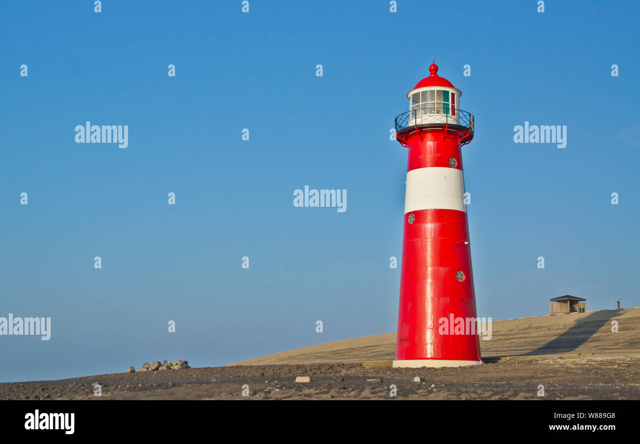 Red-white lighthouse in front of the North Sea dike. Stock Photo