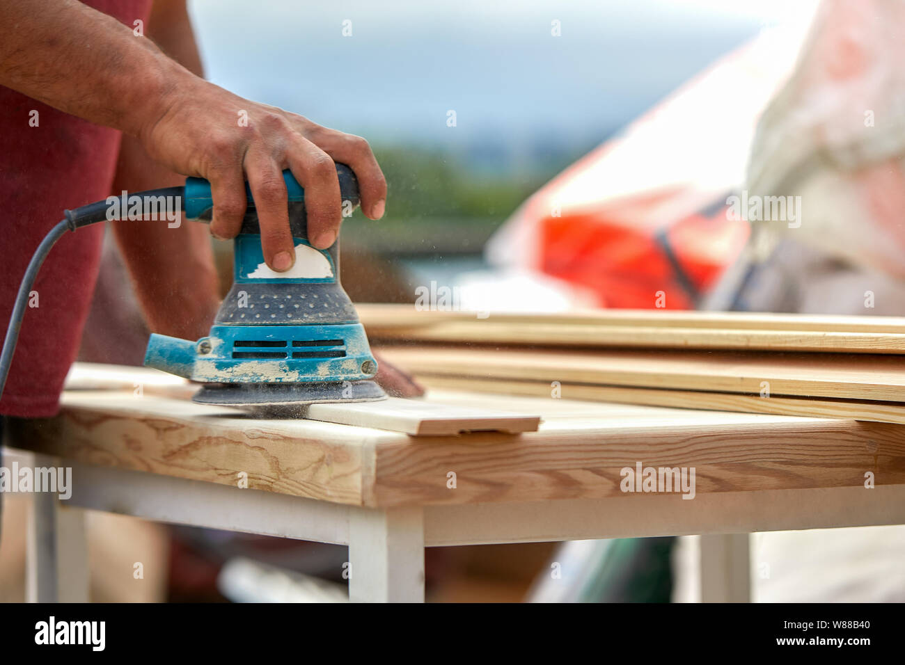 Grinder worker polishes a wooden board. Sanding boards Orbital