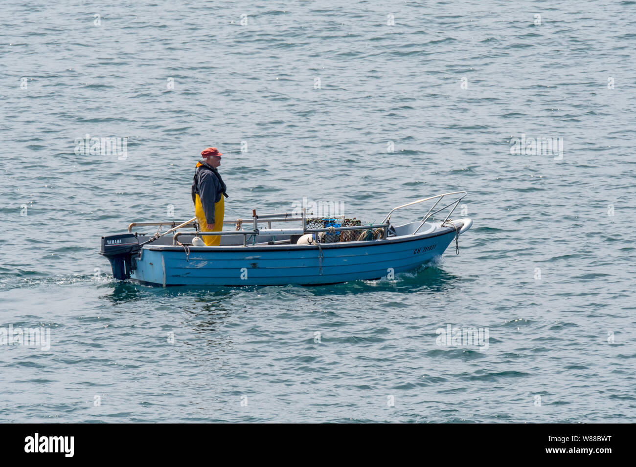 Fisherman in small fishing boat dropping / shooting lobster traps ...