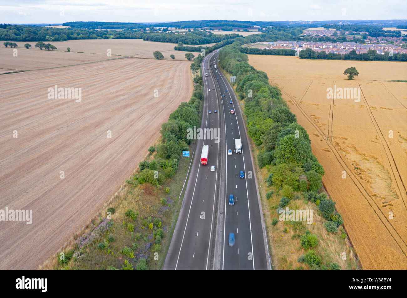 Drone shoot over dual lane motorway across ripe grain fields at summer. Shropshire in United Kingdom Stock Photo