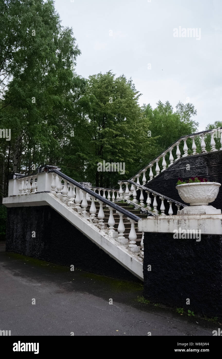 Classic old staircase with balusters on a background of green trees Stock Photo