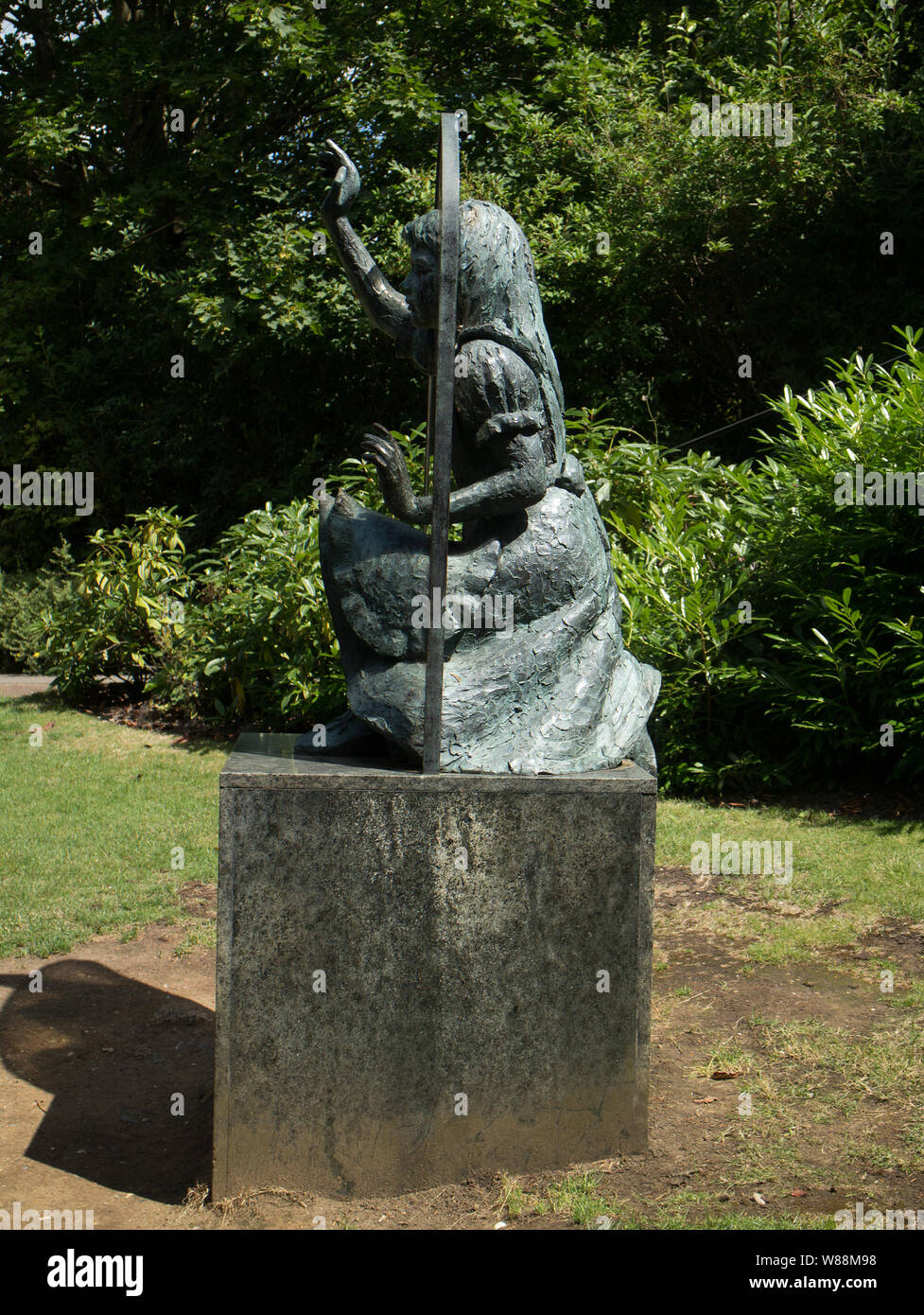 Bronze sculpture of Alice looking through the looking glass by Jean Argent in the grounds of Guildford Castle, Surrey Stock Photo