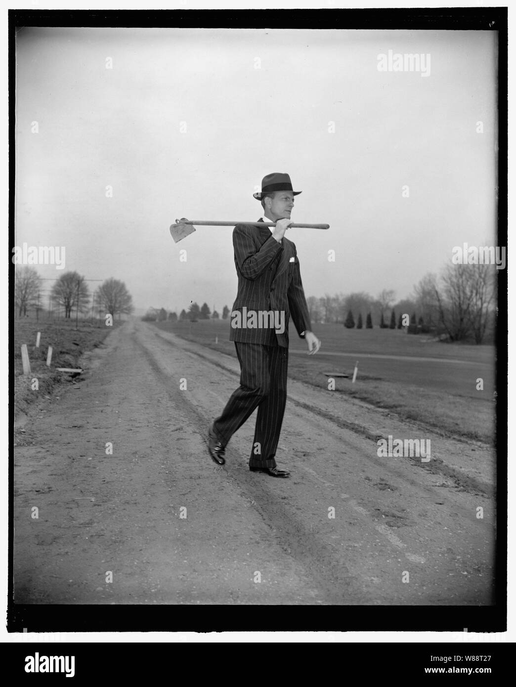 Man with the hoe, Rep. Newt Mills. Washington, D.C., Feb. 14. Rep. Newt V. Mills, of Louisiana, who was a cotton planter in his state before coming to Washington, obliged the photographer today by demonstrating how he looks at the end of a hard day of 'choppin cotton'. One must overlook the hat and business suit as the Congressman didn't bring his working clothes to Congress, 2-14-39 Stock Photo