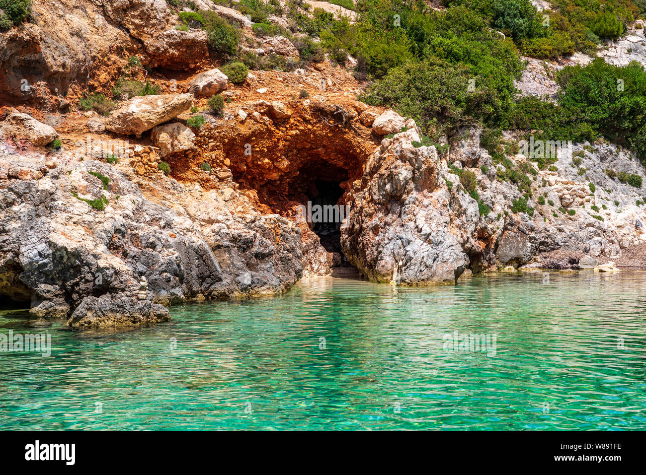 Small, paradisiacal bay of Porto Limnionas with view over the clear, turquoise water and rocks covered with bushes, Zakynthos, Greece Stock Photo