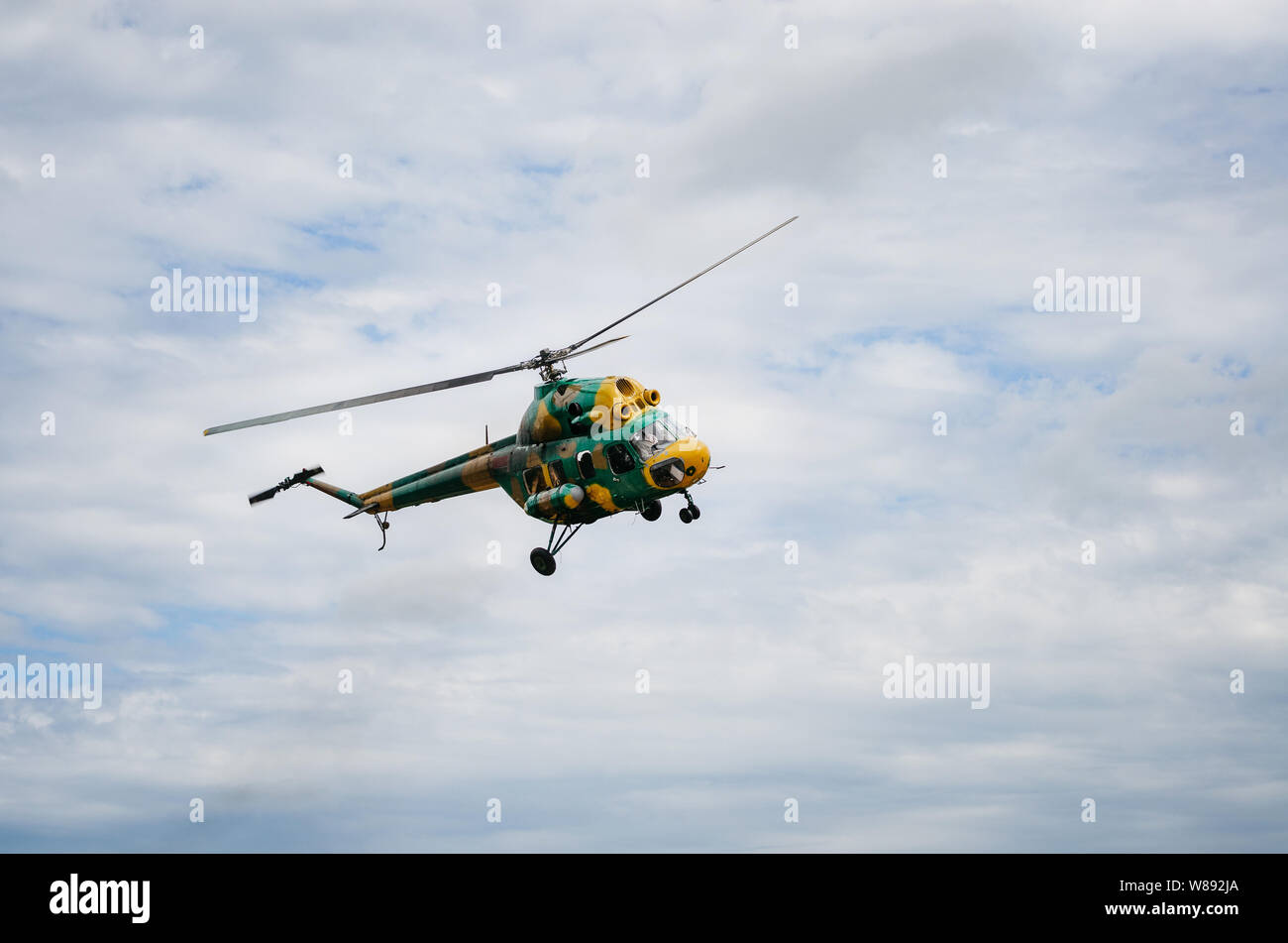 Khaki colored helicopter is flying in blue sky Stock Photo