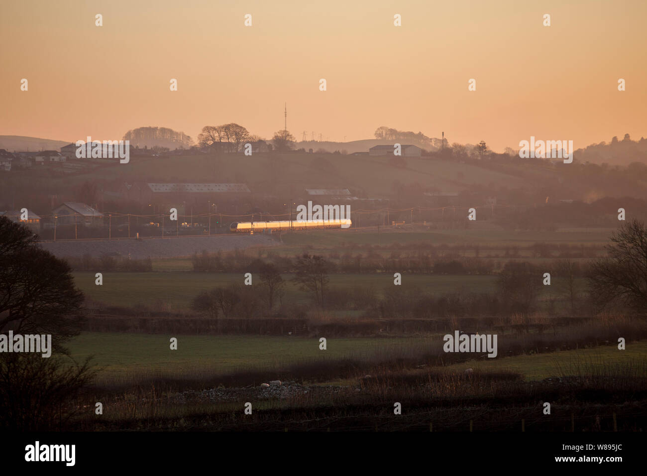 A Virgin trains class 390 Pendolino train on the west coast mainline glinting in the winter sunset near Carnforth Stock Photo