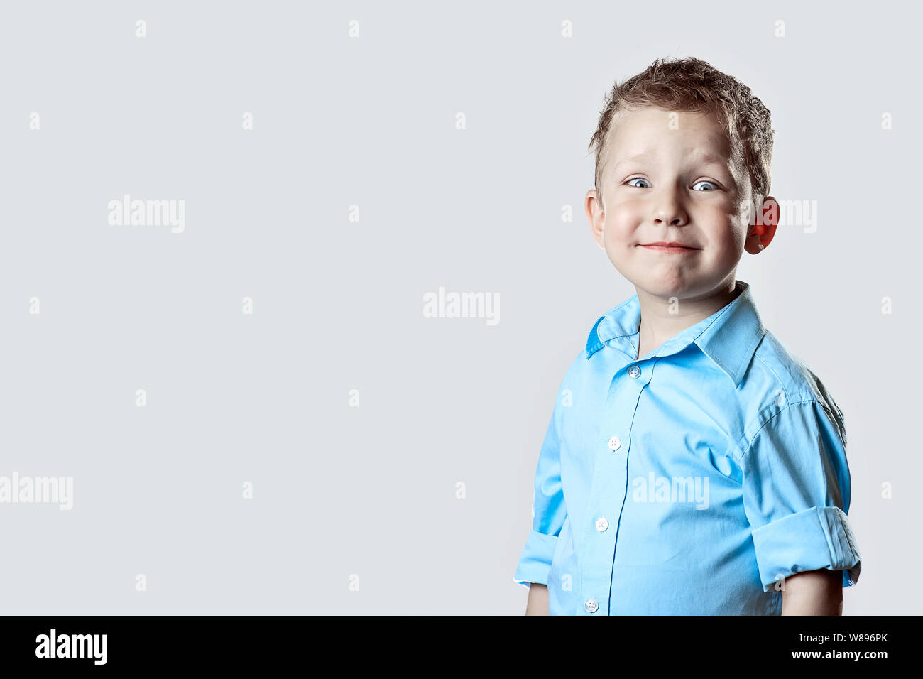 smiling happy boy in blue shirt on light background Stock Photo - Alamy