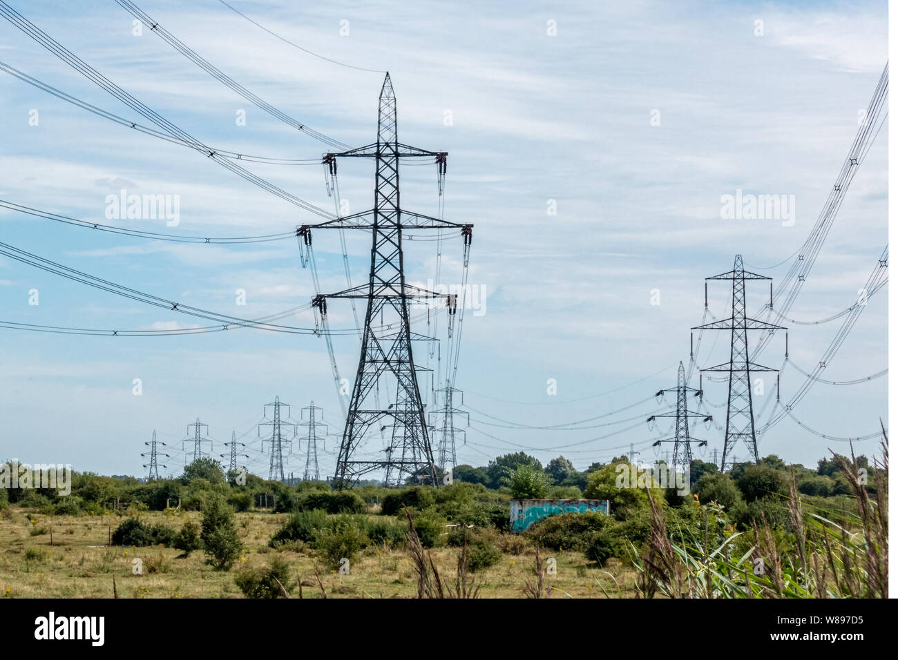 Multiple rows of overhead line power pylons in the countryside Stock Photo