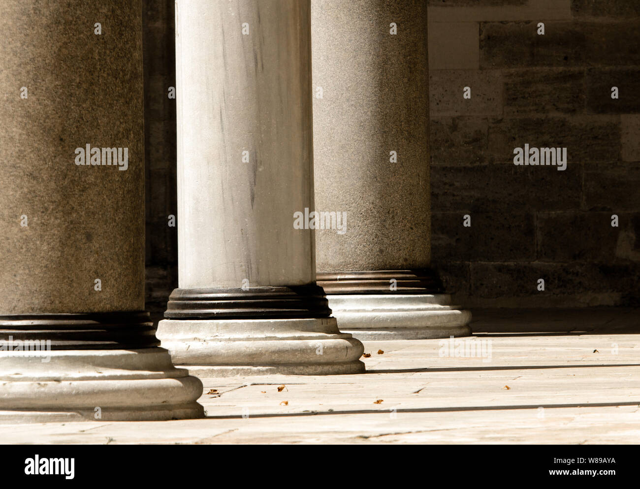 Close up of lower section of three doric order marble columns washed with sunlight in single point perspective image. Stock Photo