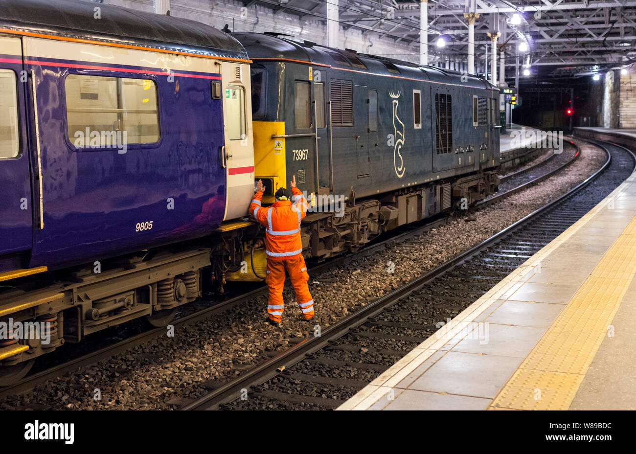 Shunter guiding the locomotive driver onto the 0443 Edinburgh - Aberdeen portion of the 2116 Caledonian sleeper train from London Euston Stock Photo