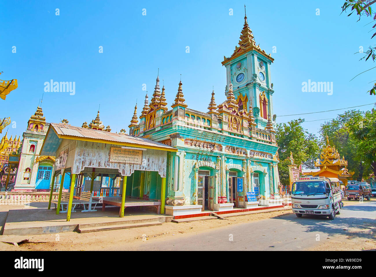 MONYWA, MYANMAR - FEBRUARY 22, 2018: The old monastic building with gilt multistaged pyatthat roof, and clock tower, located in Thanboddhay Pagoda gro Stock Photo