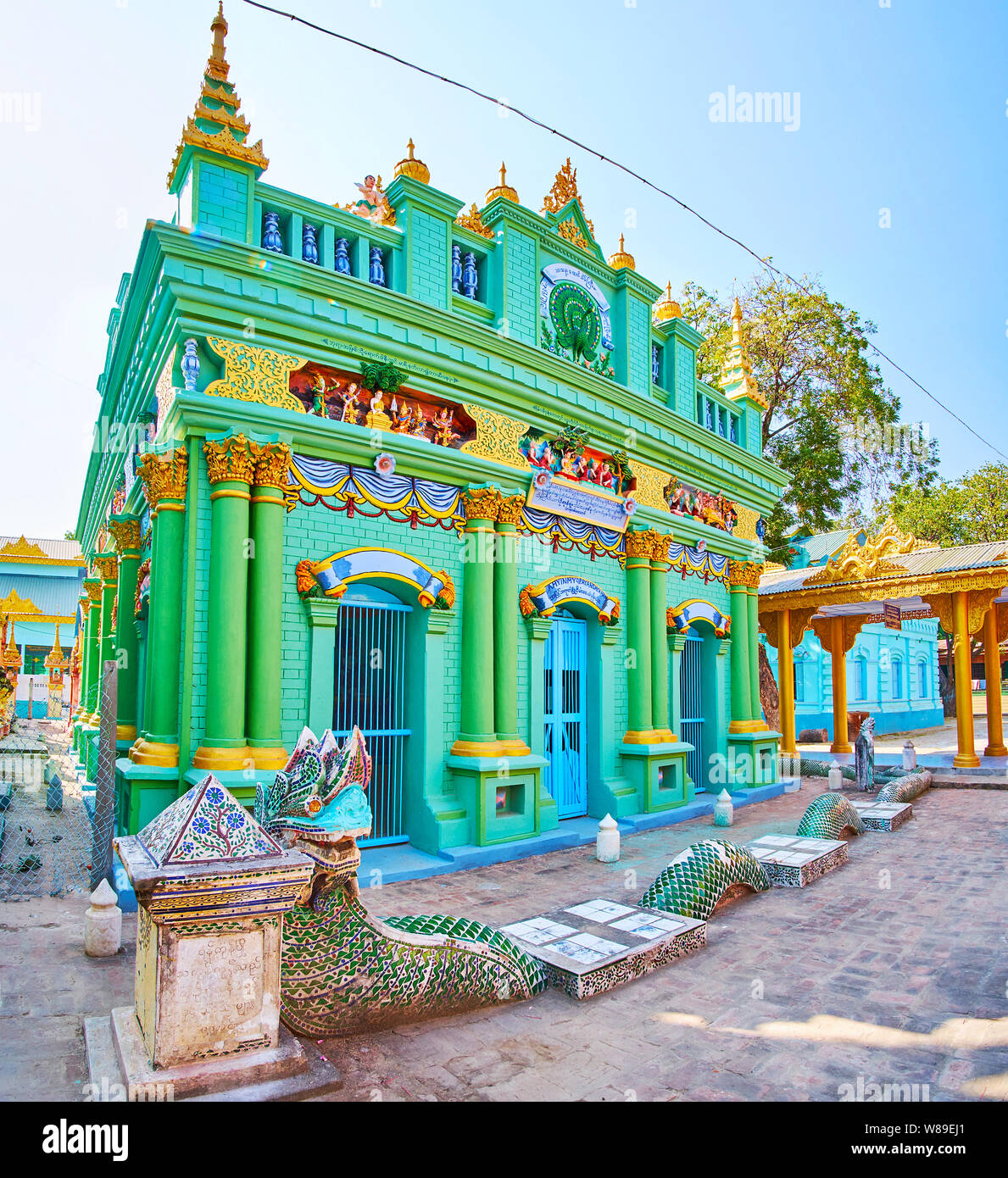 MONYWA, MYANMAR - FEBRUARY 22, 2018: The green temple of Thanboddhay monastery with relief patterns, pillars and sculpture of Naga serpent in front of Stock Photo