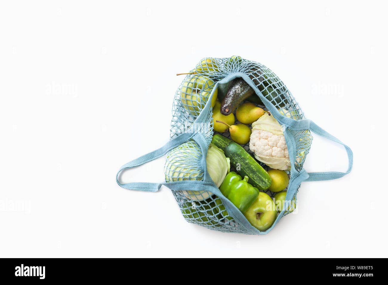 Top view of mesh shopping bag with organic eco vegetables isolated on white background. Detox and healthy eating concept. Vegetarian food.Zero waste. Stock Photo