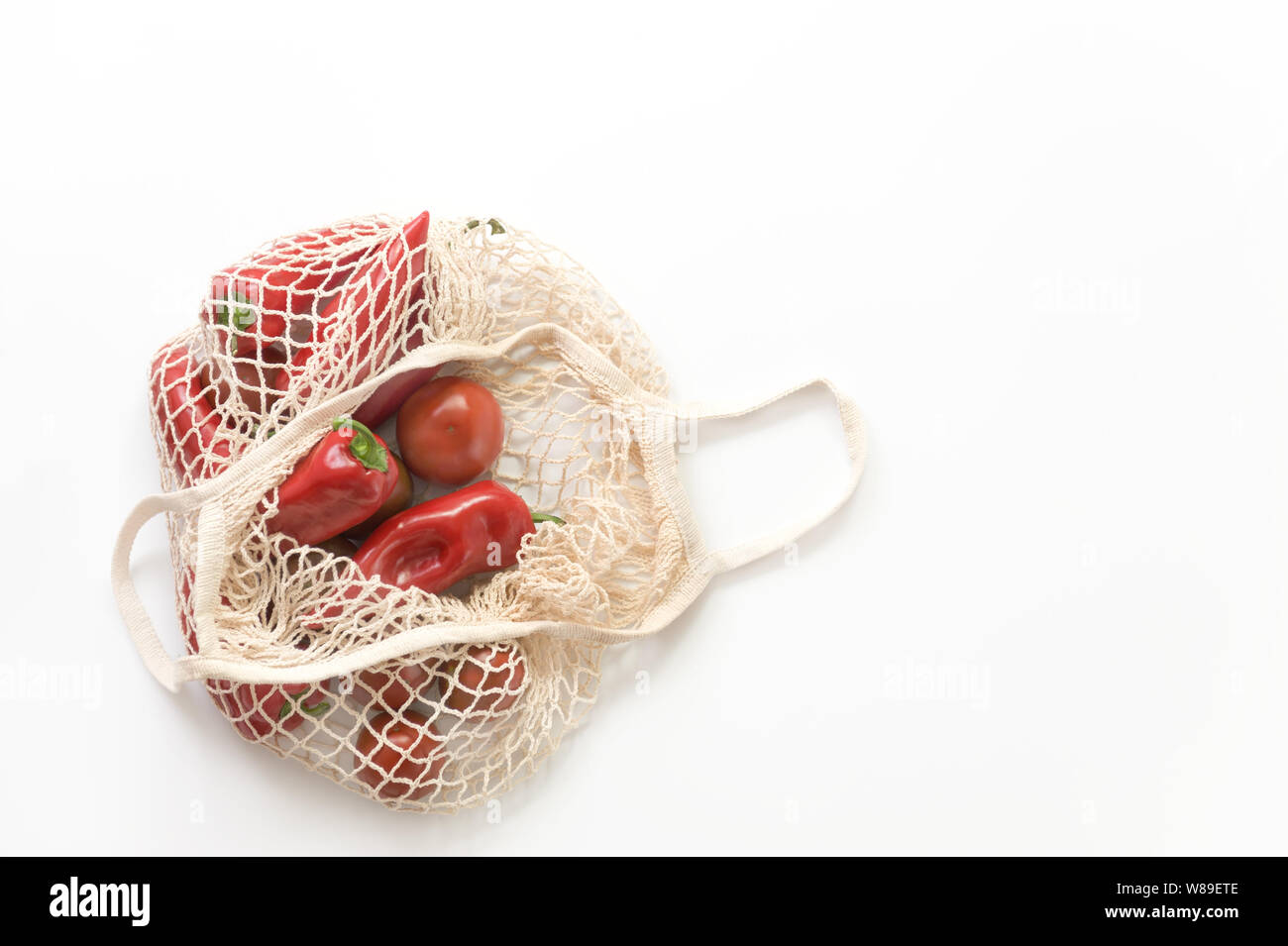 Reusable mesh string knitted shopping bag with tomatoes and red peppers. Zero Waste concept.Eco friendly. Stock Photo