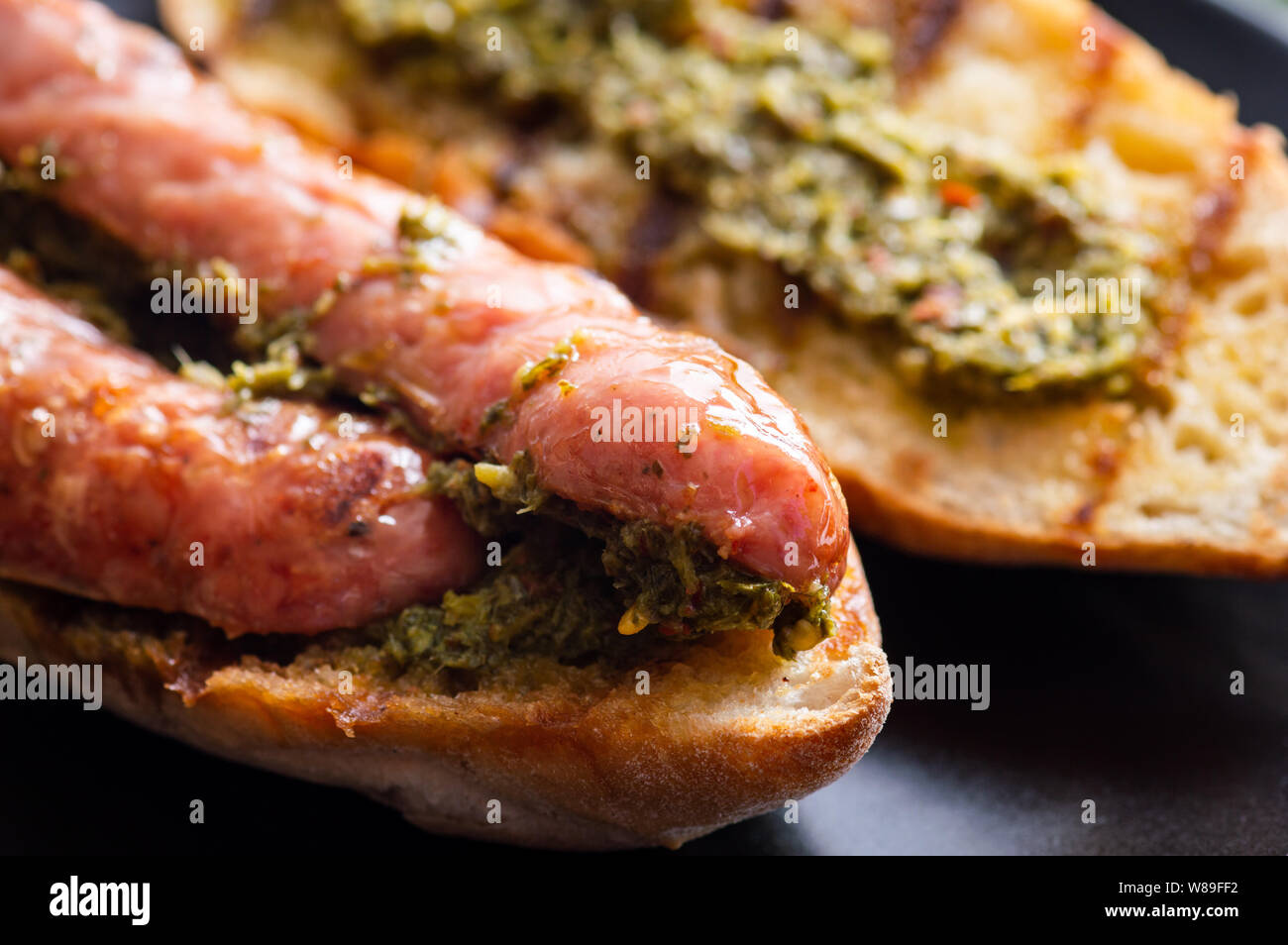 Choripan, south American style chorizo sandwich made with Argentine chorizo sausage with chimichurri, a parsley and olive oil based condiment Stock Photo