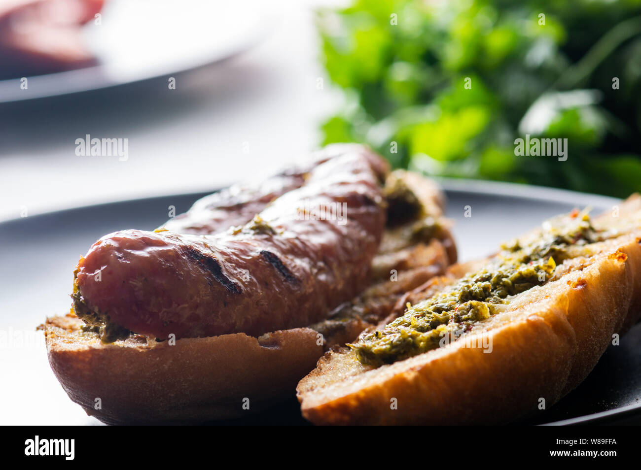 Choripan, south American style chorizo sandwich made with Argentine chorizo sausage with chimichurri, a parsley and olive oil based condiment Stock Photo