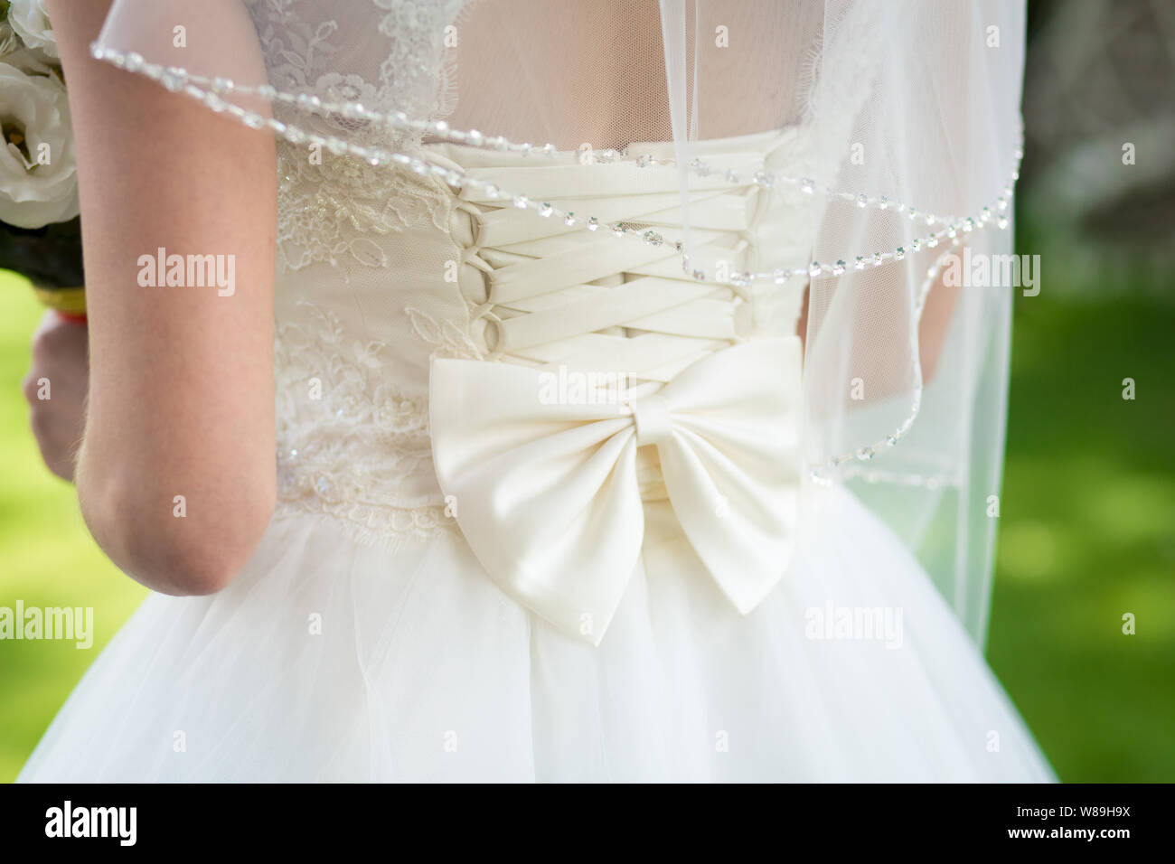 The girl in an elegant white wedding dress with bow at the back Stock