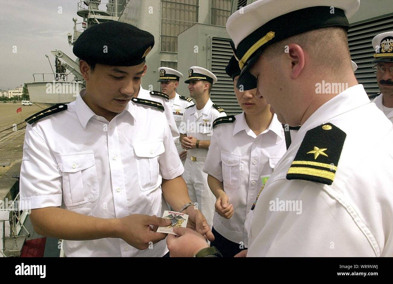 U.S. Navy Lt. j.g. Bruce Sutherland (right) gives Capt. Wen Hai Wu (left) of the People's Liberation Army (Navy) a U.S. Navy officerХs crest as a token of appreciation and goodwill during the port visit of the USS Chancellorsville (CG 62) to Qingdao, China, on Aug. 3, 2000.  Wu and other crew members of the Chinese warship Haerbin (DDG 112) are exchanging visits with the crew of the Chancellorsville while the Ticonderoga class, Aegis guided missile cruiser visits Qingdao. Stock Photo