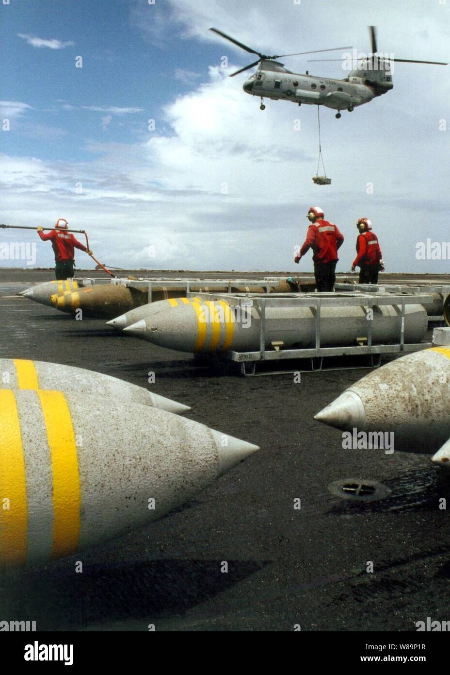 A Navy CH-46 Sea Knight helicopter delivers another pallet of bombs to the flight deck of the USS John F. Kennedy (CV 67) during an ammunition onload evolution with the USNS Mount Baker (T-AE 34) as the ships operate in the Atlantic Ocean on July 22, 2001.  Red-shirted aviation ordnancemen will move the pallets of bombs from the flight deck to the shipХs magazines below decks for storage. Stock Photo