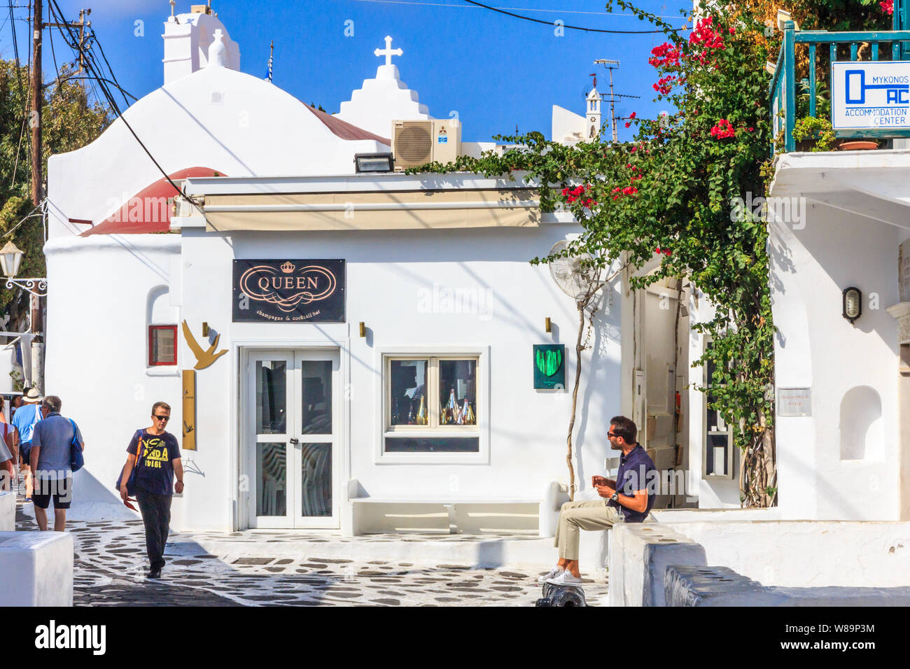 Mykonos, Greece - September 15th 2015: People in a typical narrow street. The island is a popular tourist destination. Stock Photo