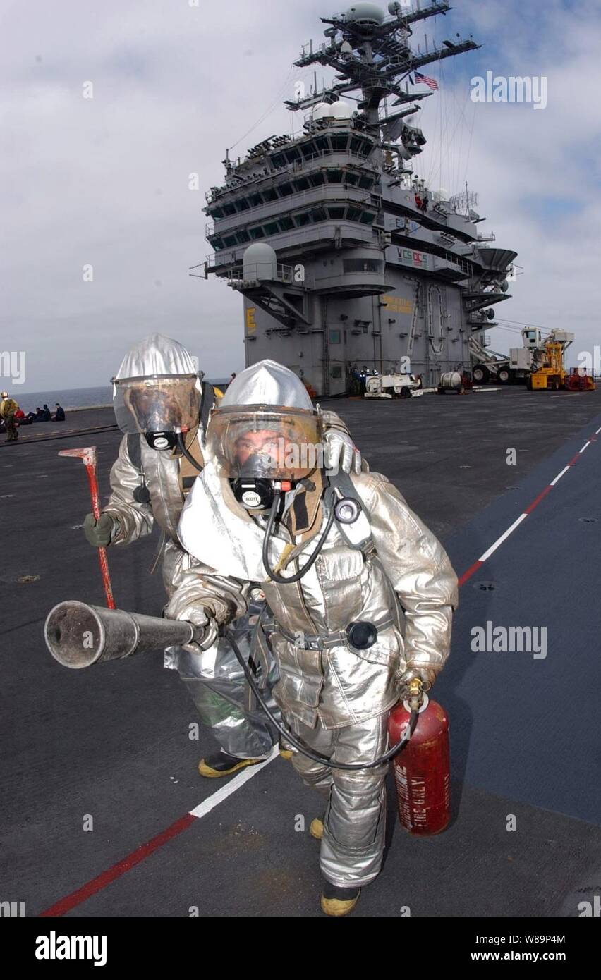 Airmen Tory Galvis (front) and Bryan Croft advance to inspect a mock aircraft crash site after the fire was contained during a mass casualty drill on the flight deck of the USS Carl Vinson (CVN 70) off the coast of Southern California on June 3, 2004. Vinson departed her homeport of Bremerton, Wash., for the coast of Southern California where she will reunite with Carrier Air Wing Nine and conduct their next phase of readiness training in preparation for an upcoming deployment. Stock Photo