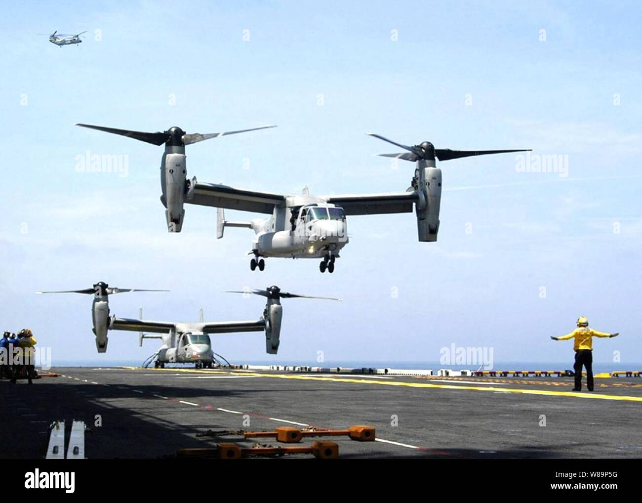 Two U.S. Navy V-22 Osprey aircraft operate from the flight deck of the USS Iwo Jima (LHD 7) during developmental testing on July 1, 2004.  The Osprey is a tilt-rotor vertical/short takeoff and landing multi-mission aircraft developed to fill joint-service, global combat operational requirements. Stock Photo