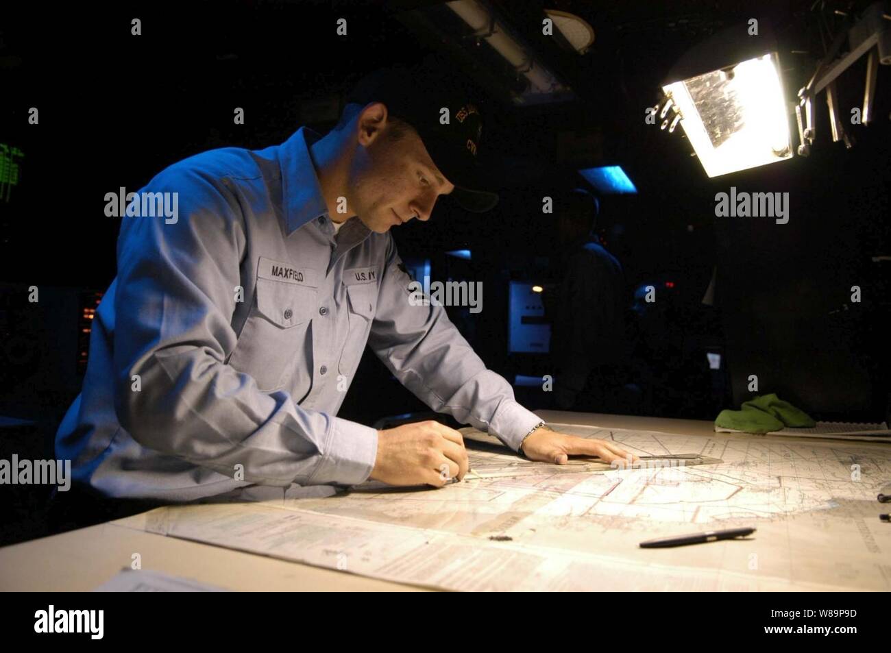 Navy Petty Officer 2nd class Ryan E. Maxfield plots the ship's position on a navigational chart aboard the aircraft carrier USS Abraham Lincoln (CVN 72) on Aug. 18, 2004.  The Lincoln is currently conducting operations in preparation for an upcoming deployment.  Ryan is a Navy operations specialist. Stock Photo