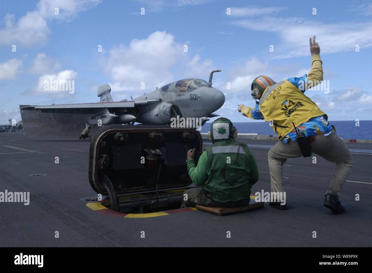A flight deck crewman known as a shooter signals an E/A-6B Prowler to go to full power before launching from the flight deck of the USS Kitty Hawk (CV 63) on Sept. 4, 2004.  The Prowler is an electronic warfare aircraft attached to Carrier Air Wing 5, the embarked air wing aboard the USS Kitty Hawk. Stock Photo
