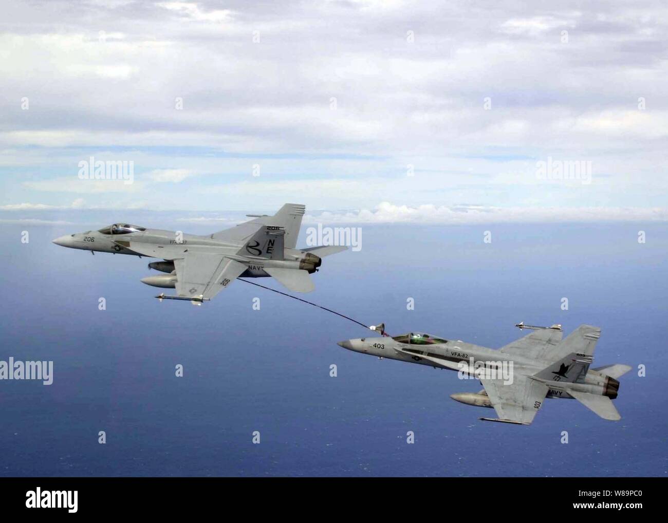 An F/A-18E Super Hornet (left) refuels an F/A-18C Hornet in-flight over the western Pacific Ocean on Oct. 28, 2004.  The Super Hornet is assigned to Strike Fighter Squadron 137 and the Hornet is assigned to Strike Fighter Squadron 82.  Both squadrons are assigned to Carrier Air Wing 2 aboard the aircraft carrier USS Abraham Lincoln (CVN 72) deployed in the western Pacific Ocean. Stock Photo