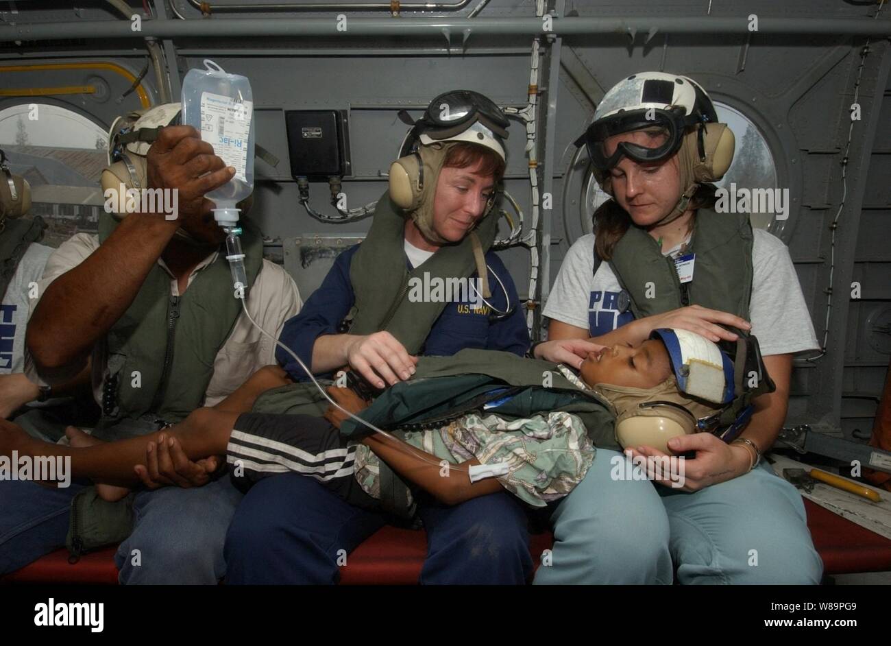U.S. Navy Nurse Cmdr. Karen McDonald (center) and a nurse from the organization Project HOPE (right) comfort a young boy suffering from a perforated appendix aboard a U.S. helicopter in Sumatra, Indonesia, on Feb. 6, 2005. The boy and his father (left) are being transported to the hospital ship USNS Mercy (T-AH 19) for medical attention.  Mercy is currently off the coast of Banda Aceh, Sumatra, Indonesia, to provide medical assistance and disaster relief to the people of Indonesia affected by the devastating tsunami that hit Southeast Asia on Dec. 26, 2004. McDonald is the Mercy's assistant di Stock Photo