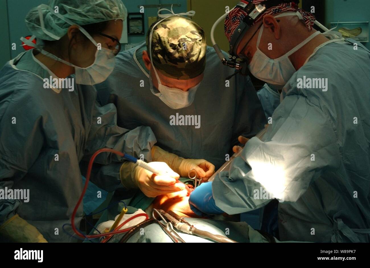 Navy Lt. Joyce Yang (left) DDS, Lt. Cmdr. Terence Johnson (center) M.D., and Cmdr. Kurt Hummeldorf (right) DDS, perform oral surgery on an Indonesian man to remove a cyst from his mouth onboard the hospital ship USNS Mercy (T-AH 19) on Feb. 18 2005.  Mercy is operating off the coast of Banda Aceh, Indonesia, providing medical assistance and disaster relief to those affected by the Dec. 26, 2004, Indian Ocean tsunami. Stock Photo