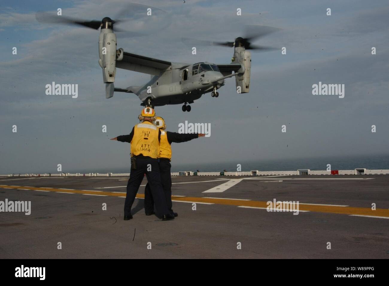 Flight deck crewmen signal the pilots of a U.S. Marine Corps MV-22 Osprey as it comes in for a landing on the USS Nassau (LHA 4) while underway in the Atlantic Ocean on March 23, 2005.  The Osprey is a vertical takeoff and landing tiltrotor aircraft designed for combat, combat support and special operations missions worldwide.  The flight deck crew of the Nassau worked with the Osprey for the first time during a weeklong familiarization at sea.  The Osprey is attached to Tilt-Rotor Operational Test Squadron 22 from Marine Corps Air Station New River, N.C. Stock Photo