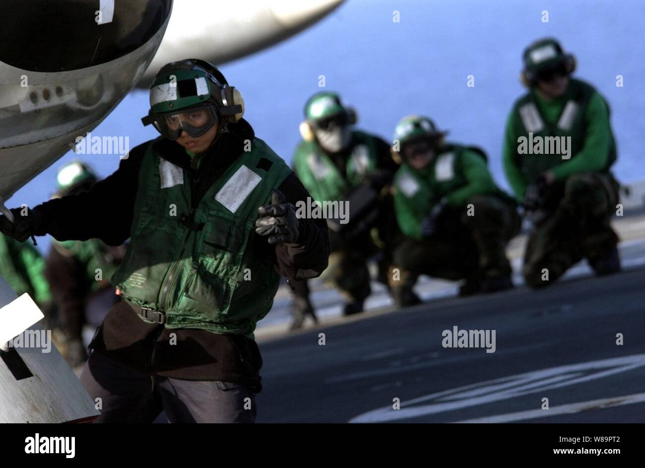 A U.S. Navy airmen directs an E-2C Hawkeye into launch position during flight operations aboard the aircraft carrier USS Ronald Reagan (CVN 76) on May 13, 2005. The Reagan and its embarked Carrier Air Wing 14 are underway in the Pacific Ocean conducting carrier qualifications.  The Hawkeye is assigned to Airborne Early Warning Squadron 113. Stock Photo