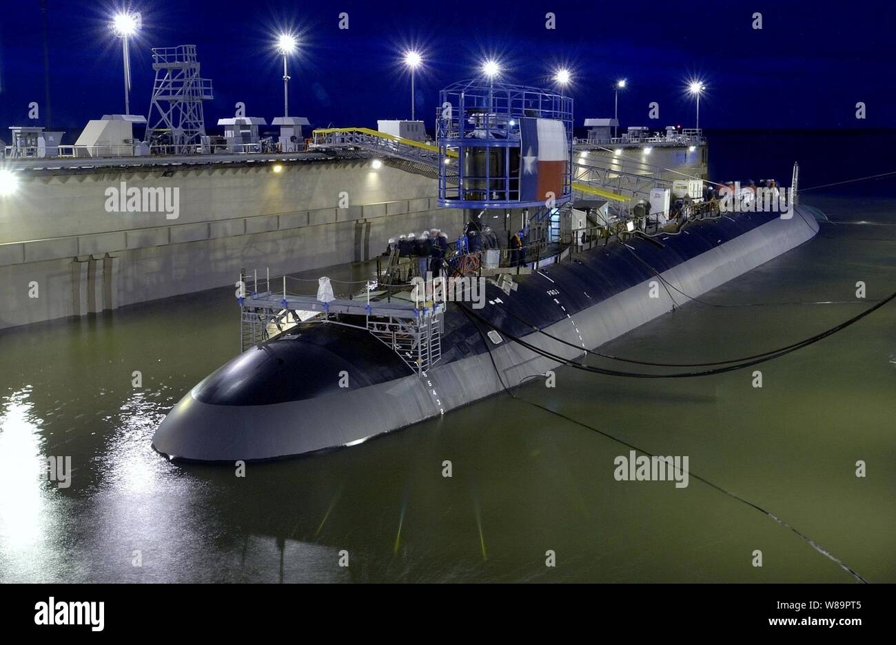 The floating dry dock at Northrop Grumman Corporation in Newport News, Va., slowly fills up with water in order to launch the Virginia-class attack submarine Texas (SSN 775) on April 9, 2005.  Tugboats will later move the submarine to the shipyard's submarine pier for fitting out.  Texas will have improved stealth capabilities, sophisticated surveillance capabilities, and Special Warfare enhancements that will enable it to meet the Navy's multi-mission requirements. Stock Photo