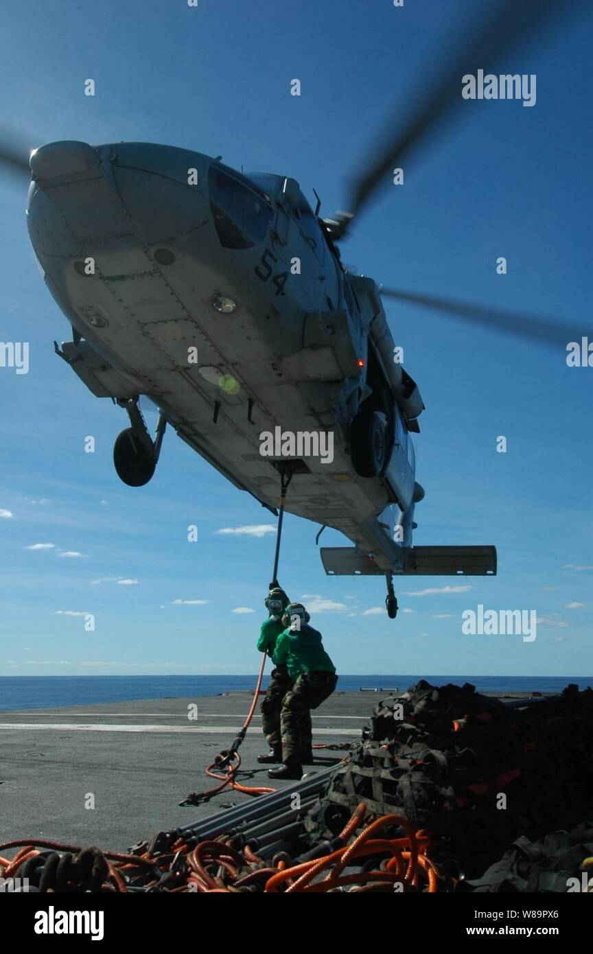Supply department personnel hook a cargo sling to an MH-60S Knighthawk helicopter as it hovers over them during a vertical replenishment operation between the USS Kitty Hawk (CV 63) and the USNS Niagara Falls (T-AFS 3) on June 18, 2005.  The aircraft carrier Kitty Hawk and the combat stores ship Niagara Falls are operating in the Coral Sea off the coast of Australia's Queensland region as part of Exercise Talisman Saber 2005.  Talisman Saber is a combined U.S.-Australia command post and field training exercise, demonstrating the U.S. and Australian commitment to the military alliance and regio Stock Photo