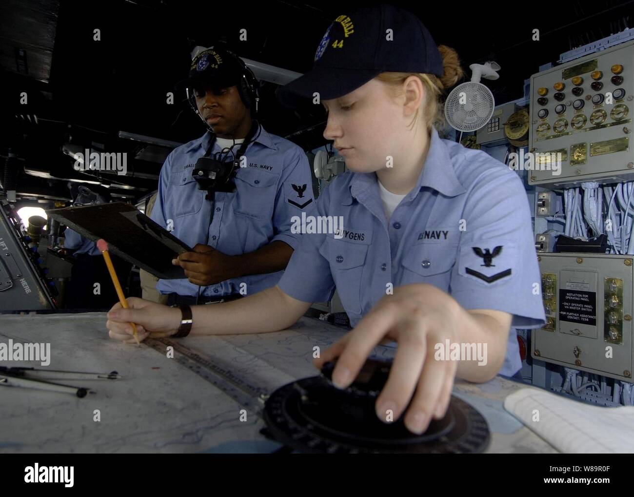 U.S. Navy Petty Officer 3rd Class Nicole Huygens (right) plots the ships course while Petty Officer 3rd Class Benjamin Smalls relays new navigational coordinates to the combat information center of the USS Gunston Hall (LSD 44) on July 17, 2005.  U.S. and Saudi Arabian Navies are participating in Exercise Nautical Union, a joint exercise in conducting Maritime Security Operations, air defense, anti-submarine warfare, surface warfare, mine counter measures, electronic warfare, replenishment at sea, and command and control. Stock Photo