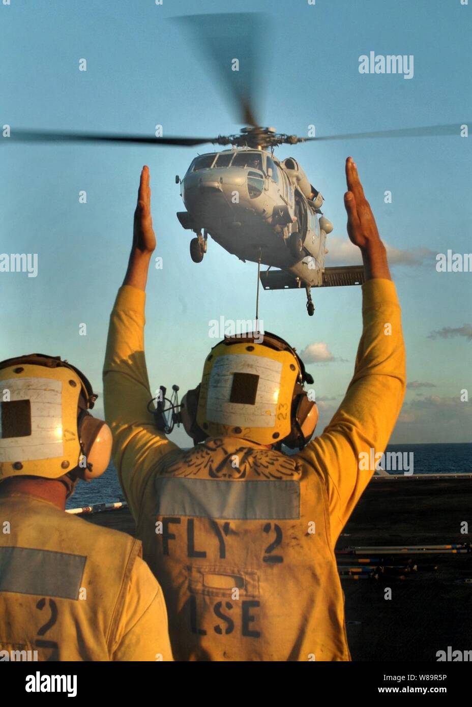 Aviation Boatswains Mate Airman Manuel Romero (right) guides a SH-60 Seahawk helicopter in for a landing aboard the USS Tarawa (LHA 1) while Aviation Boatswains Mate 2nd Class David Zavala looks on during vertical replenishment operations off the coast of San Diego, Calif., on Sept. 22, 2005. Stock Photo