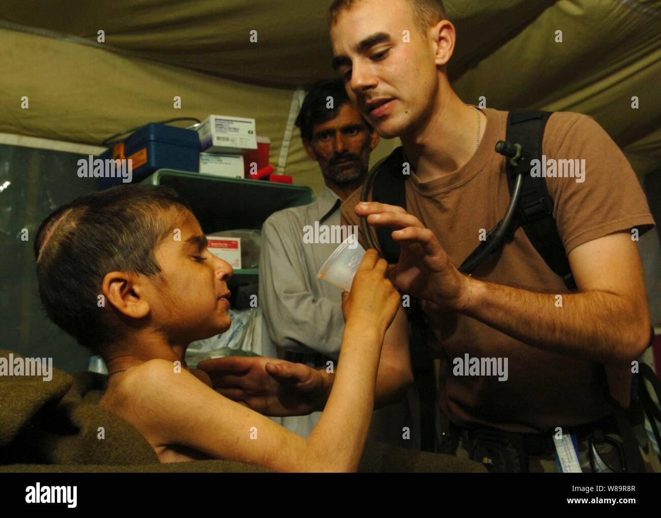 U.S. Army 1st Lt. Tory Marcon helps Riaz Sharif drink a powdered milkshake from a Meal, Ready to Eat, in Muzaffarabad, Pakistan, on Nov. 1, 2005.  The milkshake is the only food tetanus patients at the 212th Mobile Army Surgical Hospital can manage to swallow because of muscle spasms.  The Department of Defense is supporting the State Department by providing disaster relief supplies and services following the massive earthquake that struck Pakistan and parts of India and Afghanistan. Stock Photo