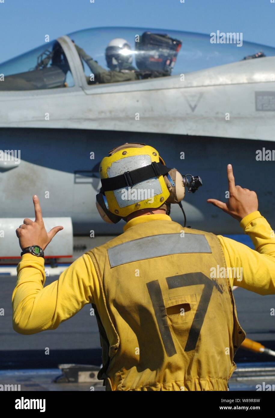A Navy Aviation Boatswain's Mate signals an F/A18 pilot as they
