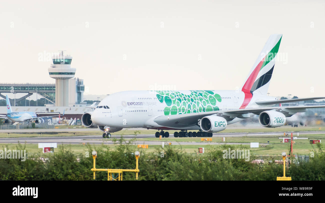 An Emirates Airlines Airbus A380-861 decorated in green EXPO 2020 livery turns off the runway in front of the air traffic control tower after landing. Stock Photo