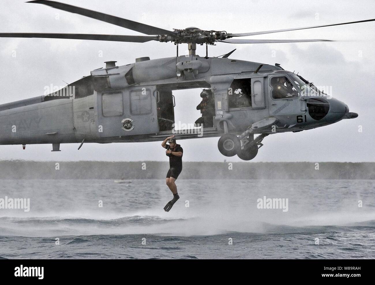 Navy Petty Officer 1st Class Eric Sutton jumps into the Pacific Ocean from a hovering MH-60S Seahawk helicopter during a search and rescue training exercise off the coast of Guam on Dec. 8, 2005.  Sutton, a Navy aviation machinist's mate, is a search and rescue swimmer attached to Helicopter Sea Combat Squadron 25 deployed to Anderson Air Force Base, Guam. Stock Photo