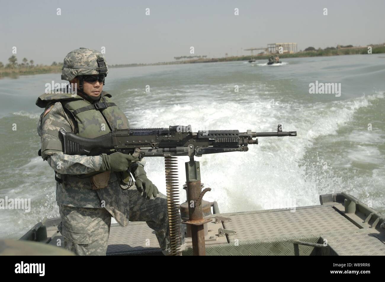 U.S. Army Master Sgt. Nardo Dedicatoria keeps an eye on the shoreline of the Euphrates River during a reconnaissance mission near Musayyib, Iraq, on March 21, 2006.  Coalition soldiers are not only patrolling the streets of Iraq, but the waterways as well.  Dedicatoria is attached to Echo Company, 1st Battalion, 67th Armored Regiment. Stock Photo