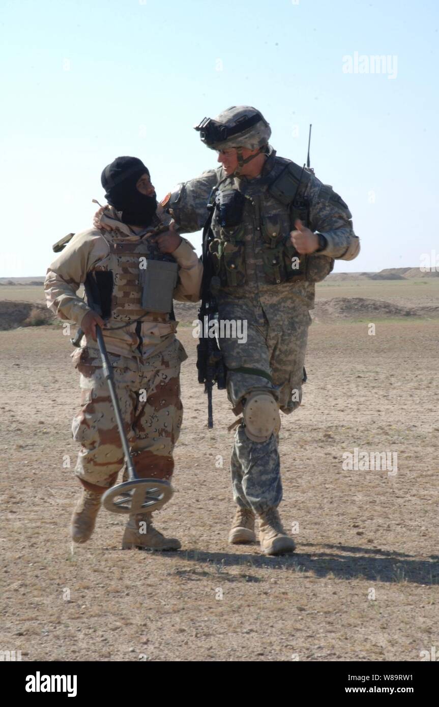 A U.S. Army soldier from Bravo Battery, 3rd Battalion, 320th Field Artillery Regiment and an Iraq army soldier from the 1st Battalion, 1st Brigade, 4th Division make small talk during a patrol in the Salah Ad Din Province, Iraq, on March 30, 2006. Stock Photo